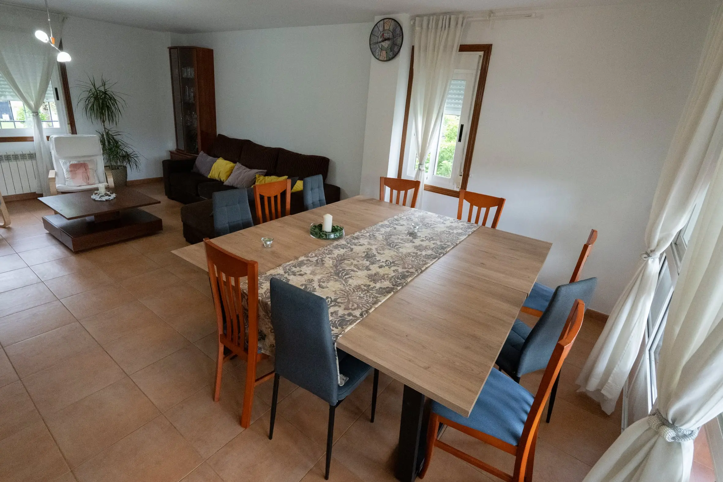 Salón comedor con mesa amplia para 10 personas, sofá y luz natural en A Casa de Blanco