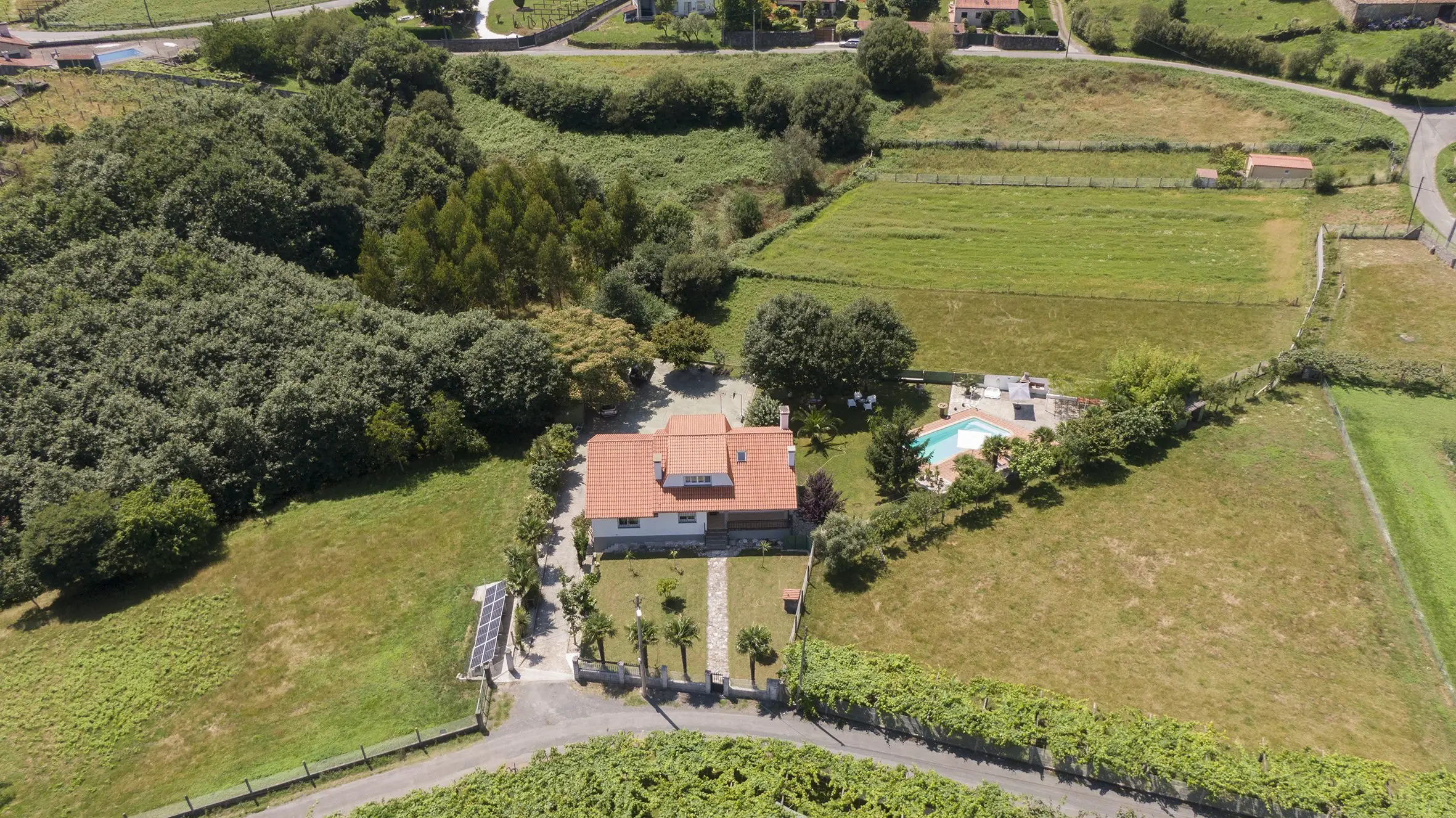 Entrada principal de la casa rural con camino de piedra y vegetación