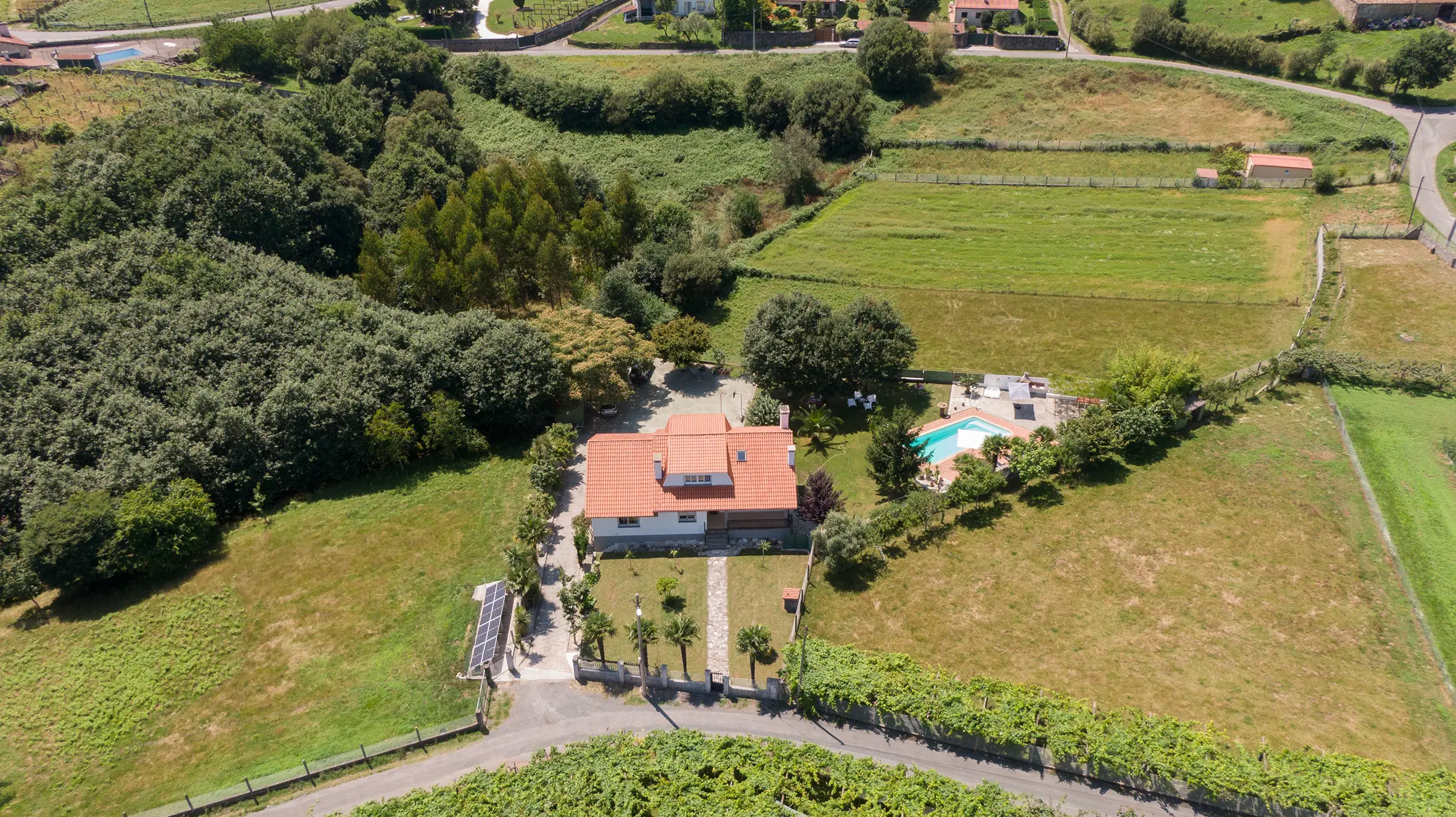 Entrada principal de la casa rural con camino de piedra y vegetación