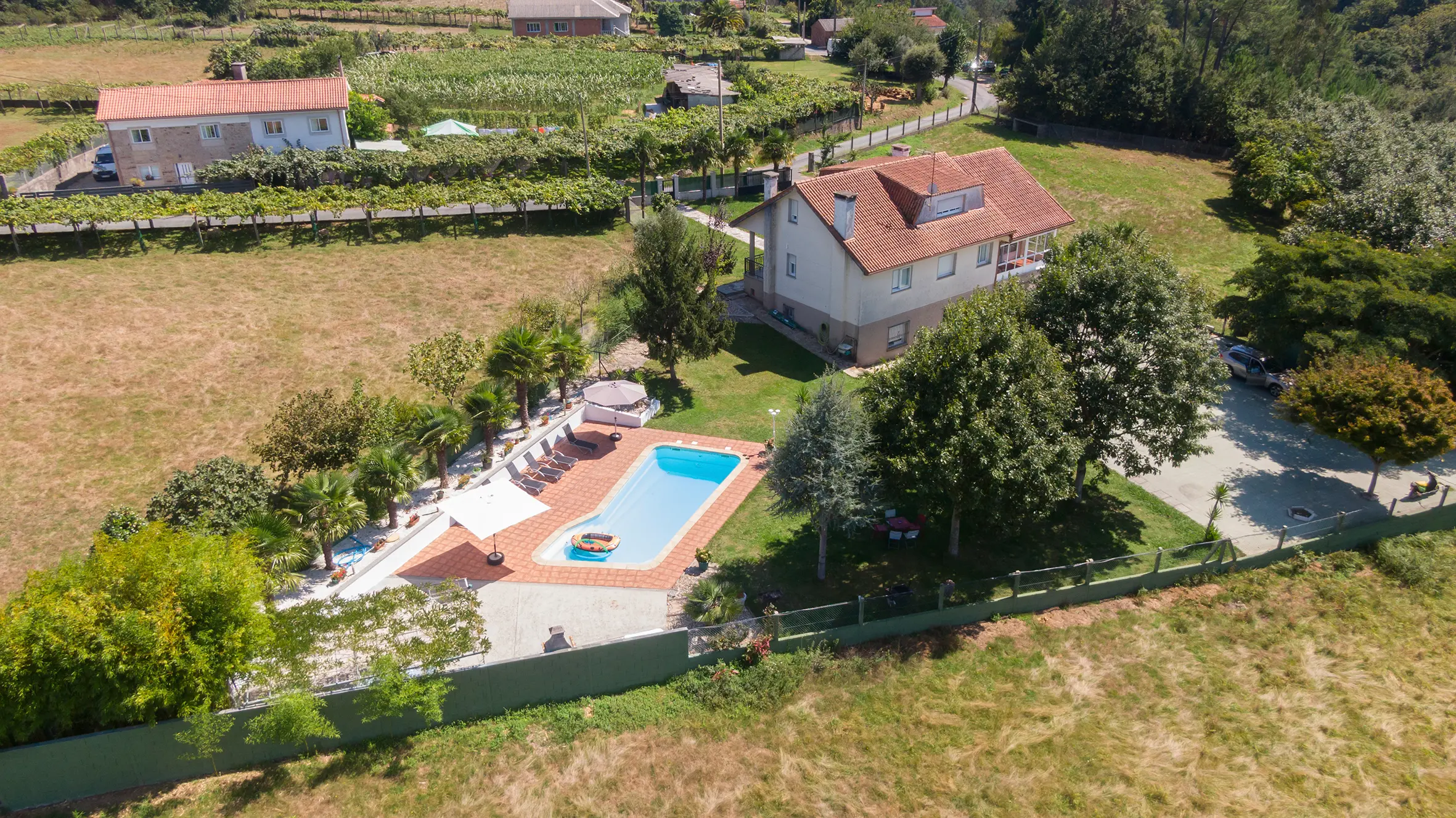 Vista panorámica de A Casa de Blanco con jardín, piscina y entorno natural en Galicia