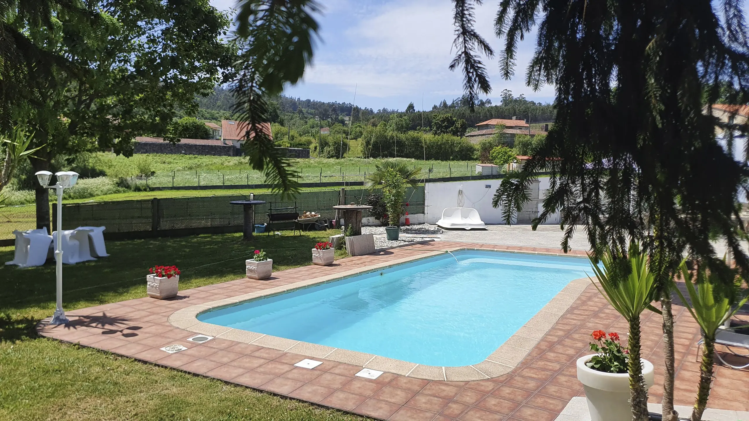 Piscina privada rodeada de jardín con tumbonas y sombrillas