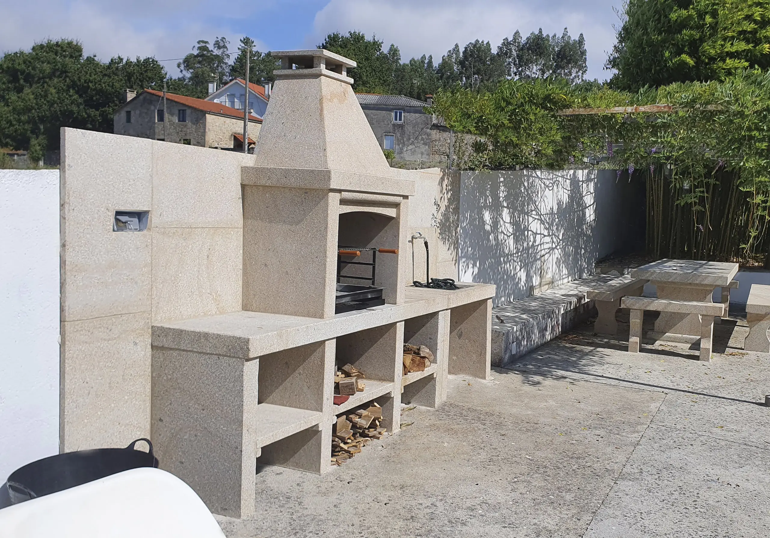 Zona de barbacoa y comedor exterior bajo porche cubierto