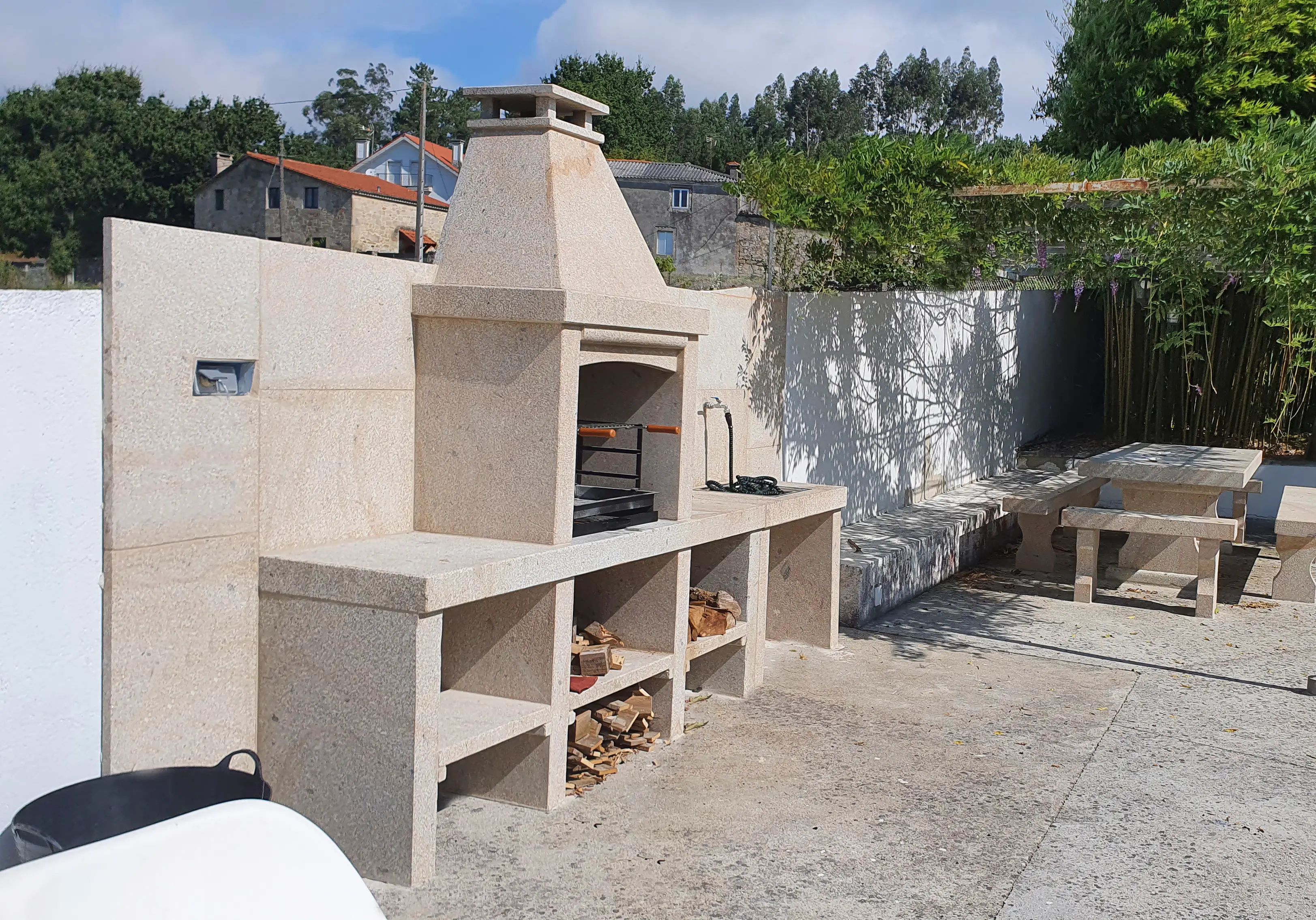 Zona de barbacoa y comedor exterior bajo porche cubierto